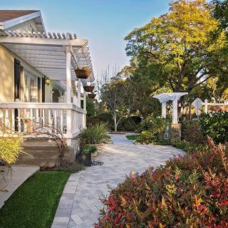 A serene view of a residential house with a well-maintained garden and a charming walkway.