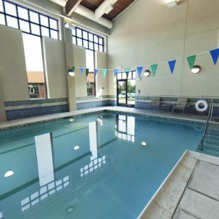 An indoor swimming pool with banners hanging from the ceiling and large windows providing natural light.