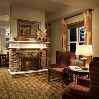 A cozy living room with a stone fireplace, warm lighting, and comfortable armchairs.