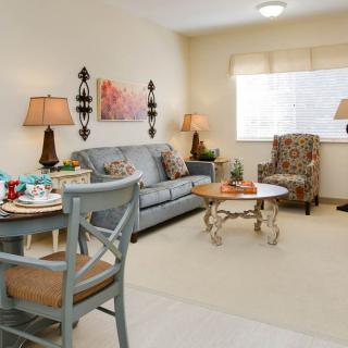 A cozy living room featuring a sofa, armchair, coffee table, and dining area.