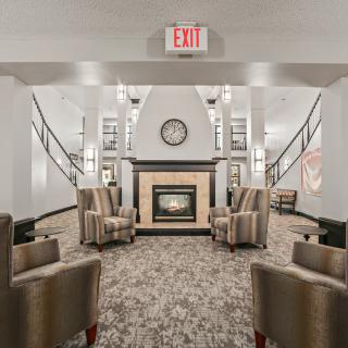A modern lobby with comfortable seating and a central fireplace.