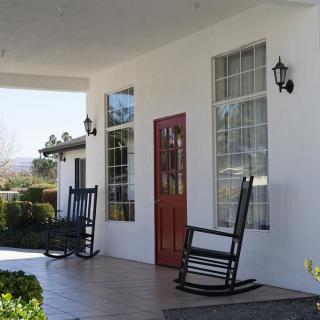 A cozy porch with rocking chairs and decorative lanterns beside a wooden front door.