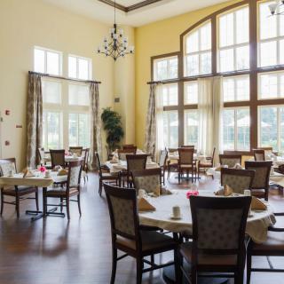 An elegant dining room with large windows and neatly arranged tables.