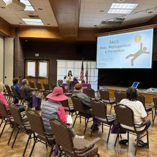 A speaker presents to an audience during an informative session in a conference room.