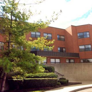 A brick building surrounded by trees under a partly cloudy sky.