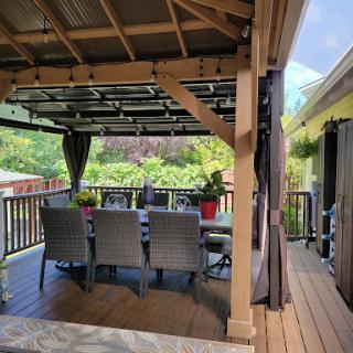 A cozy outdoor dining area with a canopy, surrounded by lush greenery.