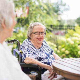 Two elderly women enjoying a sunny day outdoors, sharing smiles and conversation.
