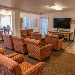 A cozy communal living room with multiple armchairs facing a television.