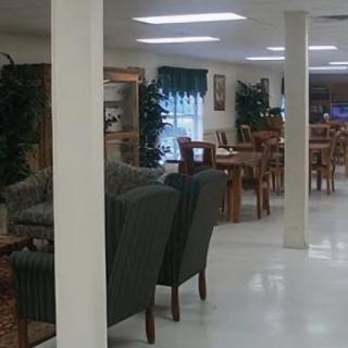 A spacious and well-lit interior featuring comfortable seating, wooden tables, and decorative plants.