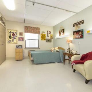 A cozy bedroom with neatly arranged furniture and wall decorations.