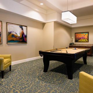 A stylish recreation room featuring a pool table, modern artwork, and comfortable seating.