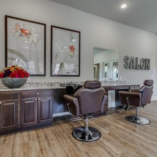 A modern salon interior featuring two styling chairs, mirrors, and vibrant artwork on the walls.