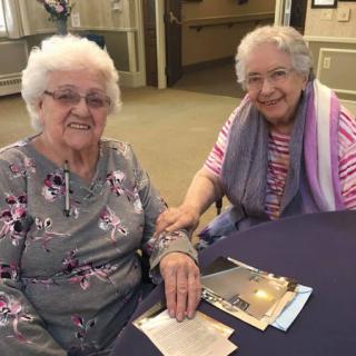 Two elderly women enjoying each other's company in a care facility.