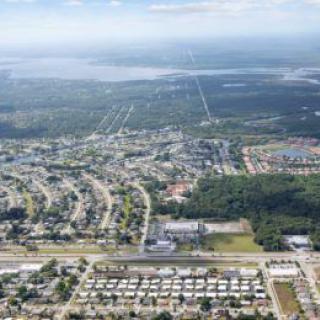 An aerial view of a suburban area with roads, buildings, and surrounding natural landscape.
