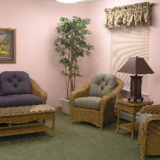 A cozy living room with wicker furniture and a potted plant.