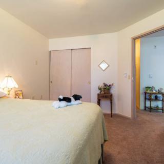 A cozy bedroom with a neatly made bed, lamp, and closet doors visible.