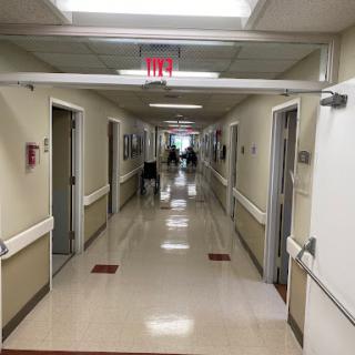 A view down a hospital hallway with lit ceiling and closed doors on either side.