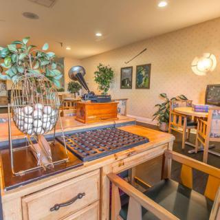 A cozy office space featuring wooden furniture, decorative plants, and framed artwork on the walls.