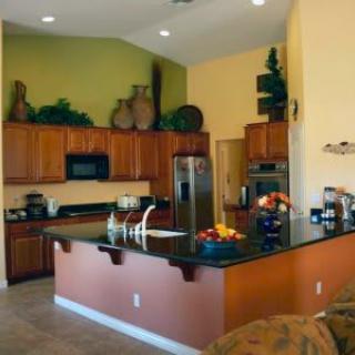 A modern kitchen with wood cabinets, stainless steel appliances, and a central island counter.