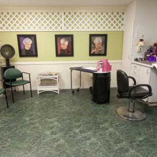 An interior view of a hair salon with chairs, a styling station, and wall art.