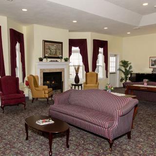 A cozy living room with classic furniture, featuring a striped sofa, armchairs by the fireplace, and elegant decor.