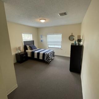 A minimalist bedroom with a bed, nightstand, and dresser.