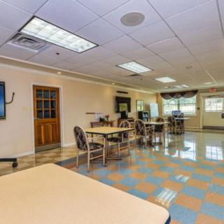 A spacious room with tables and chairs, featuring large windows and ceiling lights.