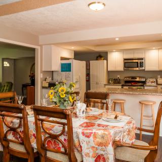 A cozy kitchen and dining area with a floral tablecloth and wooden chairs.