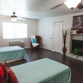 A modern bedroom with twin beds, hardwood floors, and a fireplace.