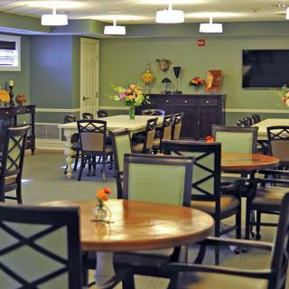 A well-lit dining room with neatly arranged tables and chairs, featuring decorative elements on the walls.