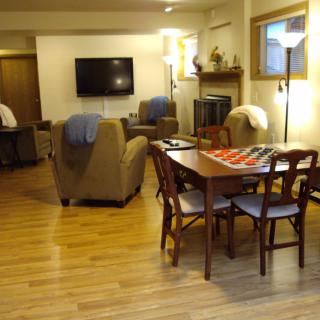 A cozy living room with a dining area, featuring comfortable seating, a television, and a wooden dining set.