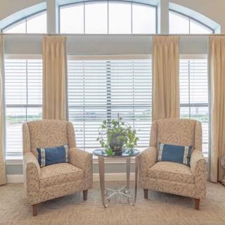 A cozy living room setup with two armchairs and a table in front of large windows.