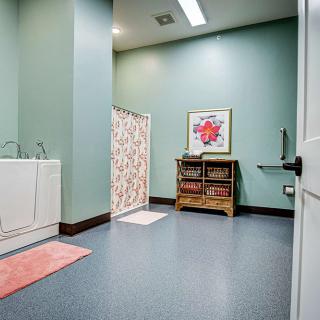 A bright and organized laundry room with mint green walls, featuring a washing machine and colorful artwork.