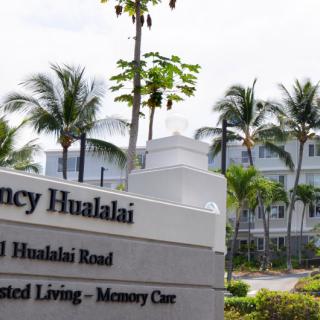 Entrance sign for Regency Hualalai, an assisted living and memory care facility surrounded by palm trees.