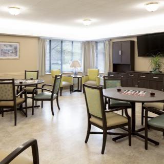 A cozy living room with multiple tables, chairs, and a television.