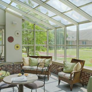 A cozy sunroom with large glass windows, comfortable seating, and ample natural light.