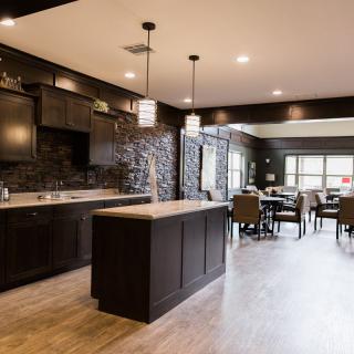 A modern kitchen and dining area with an open floor plan, featuring dark cabinets and stylish pendant lights.