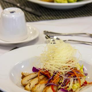 A gourmet chicken salad with colorful vegetables and garnish served on a dining table.