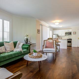 A modern open-plan living room with a green sofa and wood flooring.