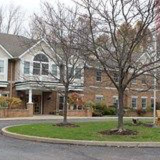 A residential-style brick building with a round driveway and bare trees in front.