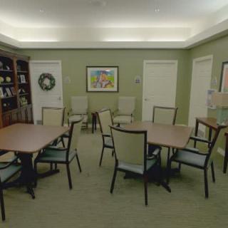 A conference room with tables and chairs arranged for a meeting, featuring a bookcase and artwork on the walls.