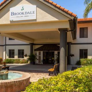 The front entrance of a Brookdale building with landscaping and a fountain.