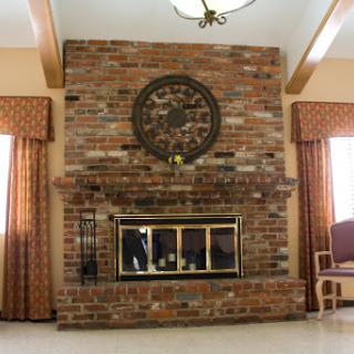 A cozy living room featuring a rustic brick fireplace and a stylish round clock.