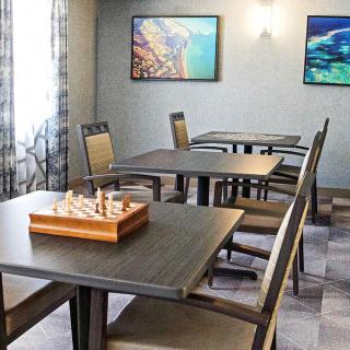 A calm room with tables and chairs, featuring a chess board and wall art.