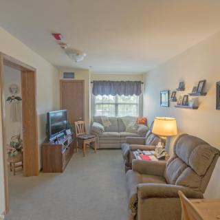 Cozy living room with sofa, armchairs, and a television.