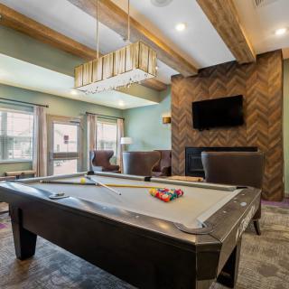 A stylish recreation room featuring a pool table, modern decor, and a wall-mounted television.
