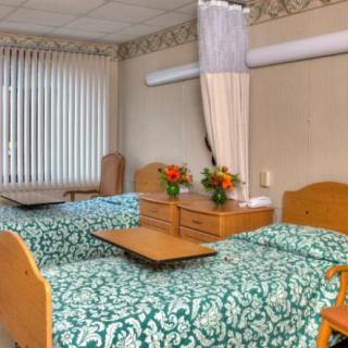 A hospital room with two beds, decorated with flowers, and equipped with privacy curtains.