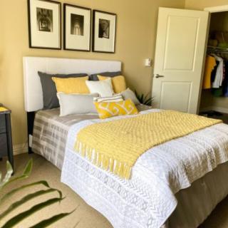 A cozy bedroom with yellow accents and neatly arranged bedding.