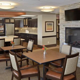 A modern dining area featuring a fireplace, television, and kitchen facilities.