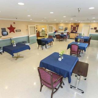 A spacious dining area with neatly arranged tables and chairs, covered in blue tablecloths.